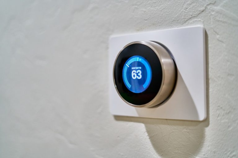 Nest smart thermostat mounted on wall displaying temperature